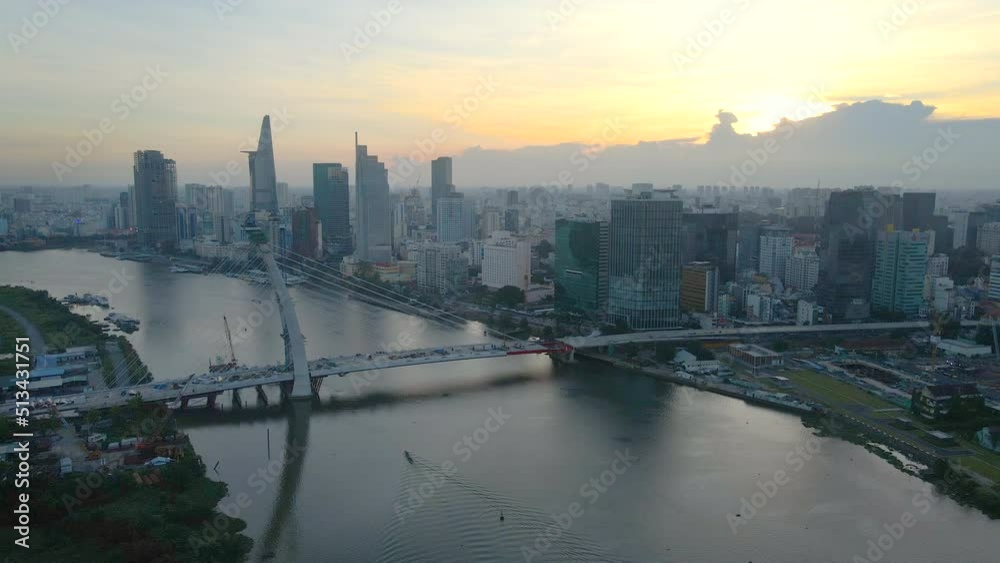 Flying at Sunset over Nearly Constructed Bridge on Saigon River in Downtown of Ho Chi Minh City Vietnam, Towers and Buildings in Background Flying at Sunset over Nearly Constructed Bridge on Saigon River in Downtown of Ho Chi Minh City Vietnam, Towers and Buildings in Background