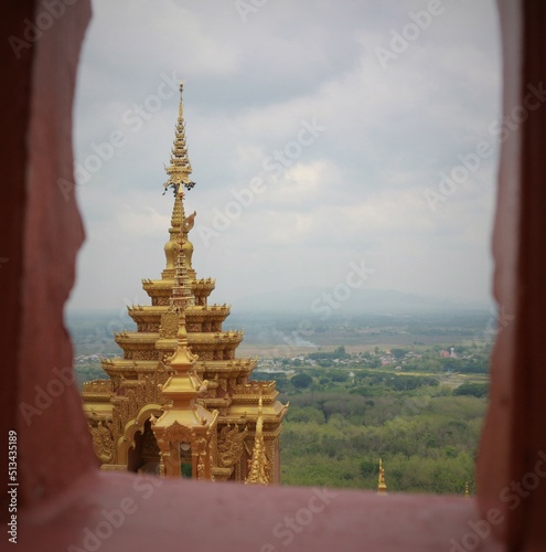 Picture of the top of a pagoda on a mountain taken through a window.