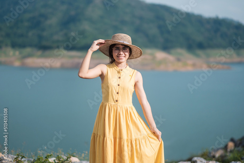 Asian Woman in yellow dress and hat Traveling at outdoor, Happy traveler looking to Khun dan Prakarnchon dam. landmark and popular for tourists attractions in Nakhon Nayok, Thailand © Jo Panuwat D