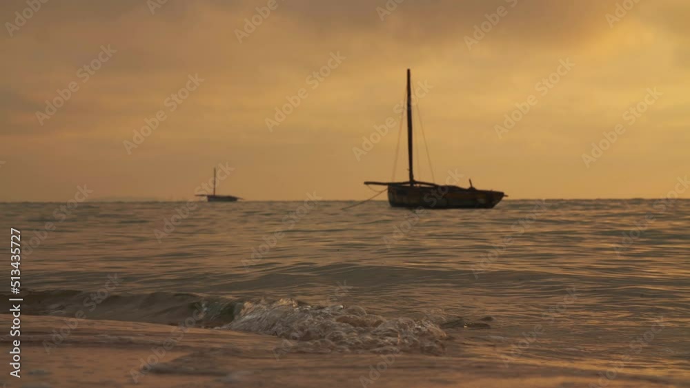 Silhouettes Of Empty Fishing Boats During Warm Yellow And Orange Golden Hour Sunset With Small Waves Breaking On Beach Shore in Vilanculos Bazaruto Archipelago, Mozambique, Africa. Silhouettes Of Empty Fishing Boats During Warm Yellow And Orange Golden Hour Sunset With Small Waves Breaking On Beach Shore in Vilanculos Bazaruto Archipelago, Mozambique, Africa.