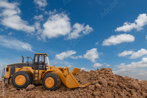 Wheel loader are digging the soil in the construction site on sky background ,with white fluffy cloud © chaphot
