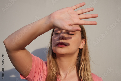Canvas Print woman closes her hand from bright sunlight, a shadow on her face