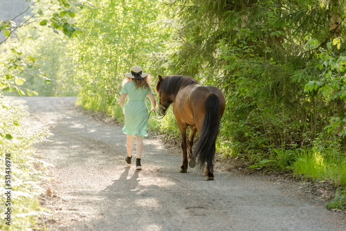 Icelandic horse on gravel road with young woman. Shot in the evening middle of the summer in Finland