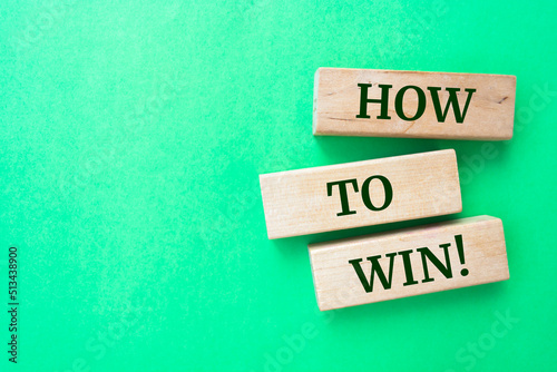 How to win! words on wooden blocks on green background.