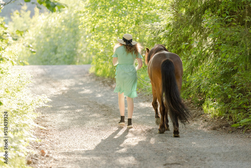 Icelandic horse on gravel road with young woman. Shot in the evening middle of the summer in Finland © AnttiJussi