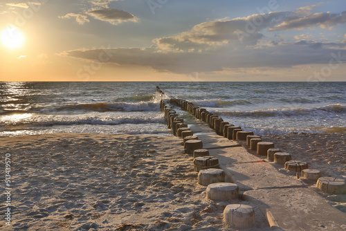 Wooden groynes in the water of the Baltic Sea by the beach at sunset