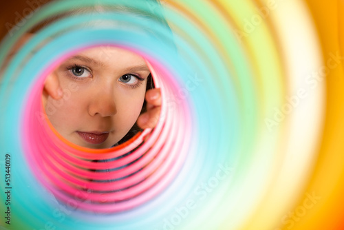Teen girl play rainbow slinky toy on color background