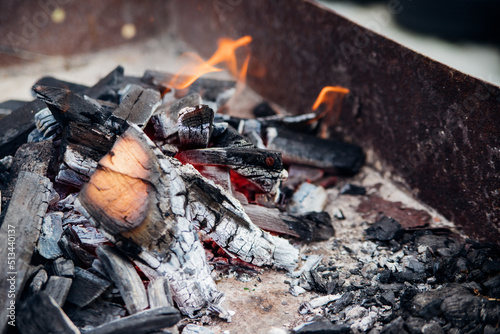 A brightly burning bonfire with a red flame made from wood in an outdoor grill.An adventurous lifestyle in travel. Active weekend recreation in the wild outdoors.