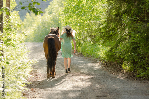 Icelandic horse on gravel road with young woman. Shot in the evening middle of the summer in Finland © AnttiJussi
