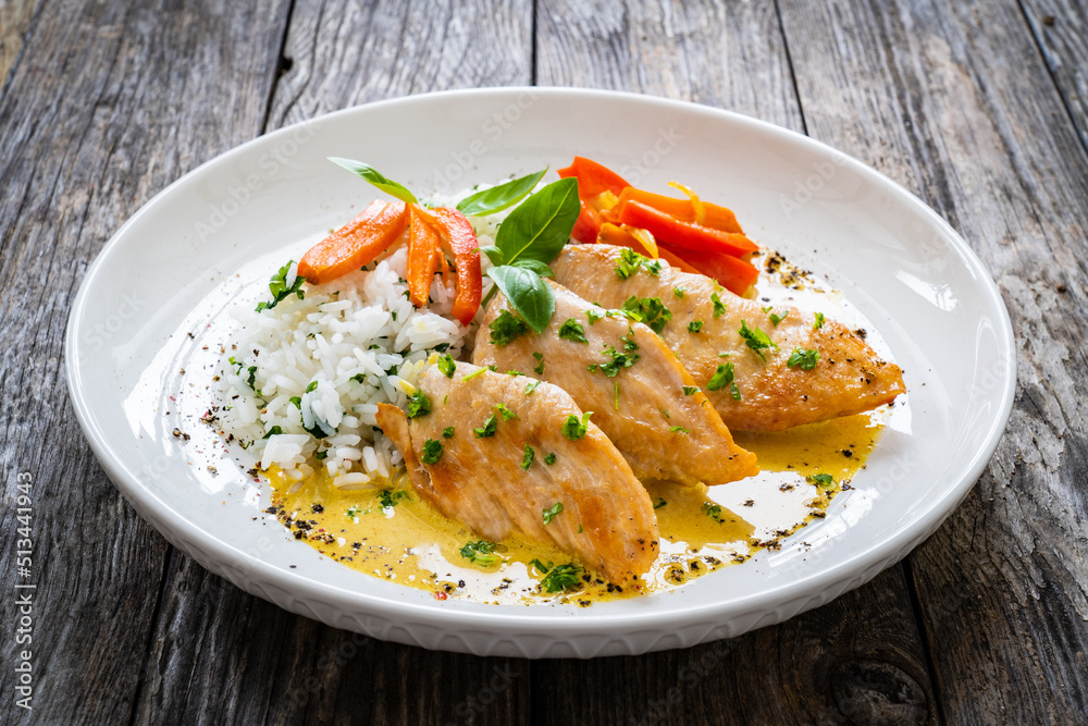 Fried chicken breasts in curry sauce with white rice on wooden table
Fried chicken breasts in curry sauce with white rice on wooden table
