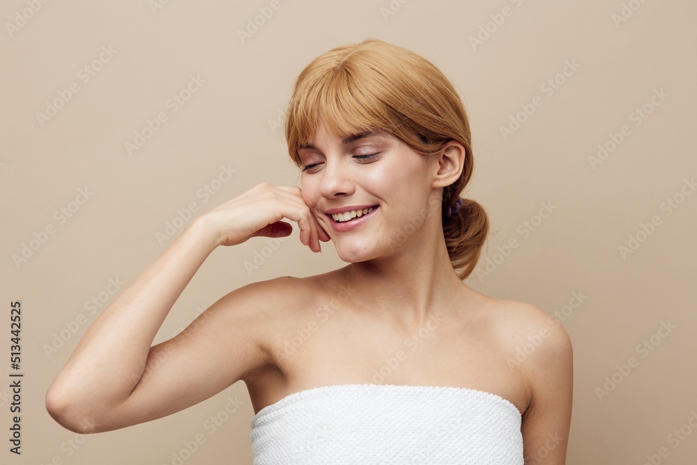 a pleasant, relaxed, attractive woman stands on a beige background and closes her eyes with pleasure and touches her face with her hand a pleasant, relaxed, attractive woman stands on a beige background and closes her eyes with pleasure and touches her face with her hand