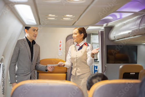 Cabin crew or air hostess working in airplane. Friendly air hostess greeting handsome businessman passenger in airplane. Airline transportation and tourism concept