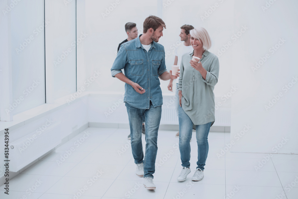 Fototapeta premium employees with coffee glasses passing through the corridor of the office