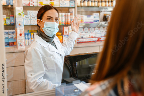 White apothecary wearing face mask working with customer