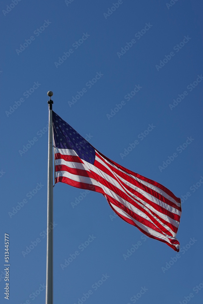 The United States flag waving high in the blue sky