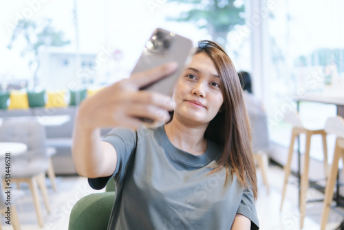 Woman use a smartphone to take a selfie in a coffee shop
