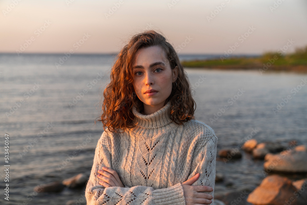 Young woman standing with arms crossed at sunset Young woman standing with arms crossed at sunset