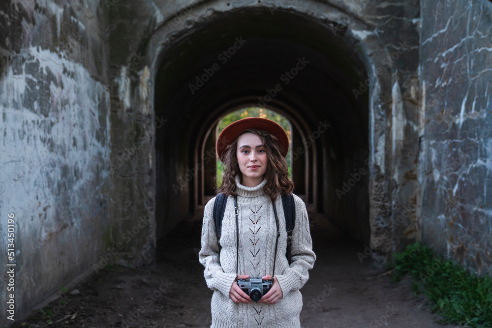 Young woman with camera standing in front of tunnel Young woman with camera standing in front of tunnel