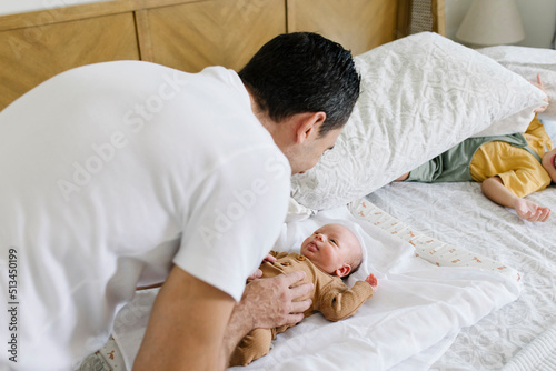 Smiling man playing with baby on bed at home photo