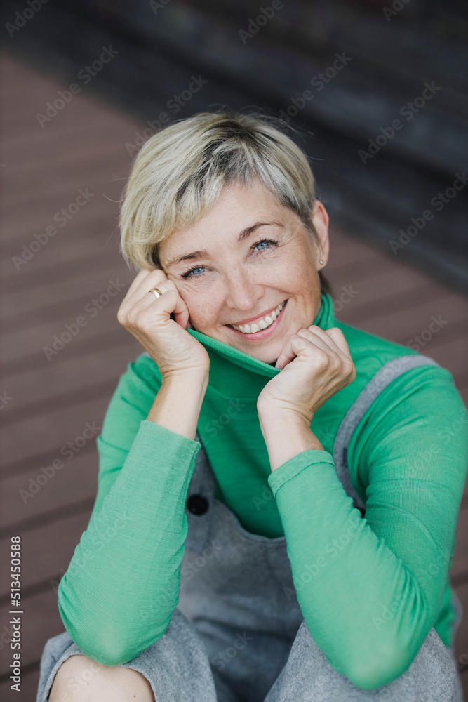 Happy mature woman with short blond hair wearing bib overalls