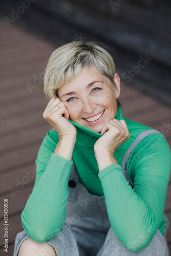 Happy mature woman with short blond hair wearing bib overalls photo