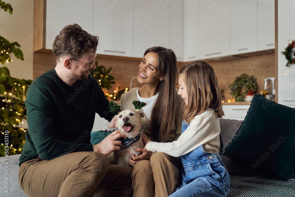 Smiling family with dog enjoying Christmas time together at home
