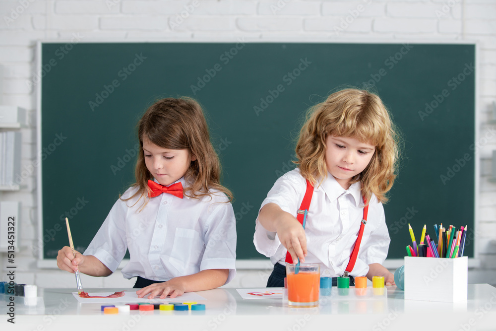 School children drawing a colorful pictures with pencil crayons in classroom. Portrait of cute pupils enjoying art and craft lesson. Siblings drawing with pencil and paints. School children drawing a colorful pictures with pencil crayons in classroom. Portrait of cute pupils enjoying art and craft lesson. Siblings drawing with pencil and paints.