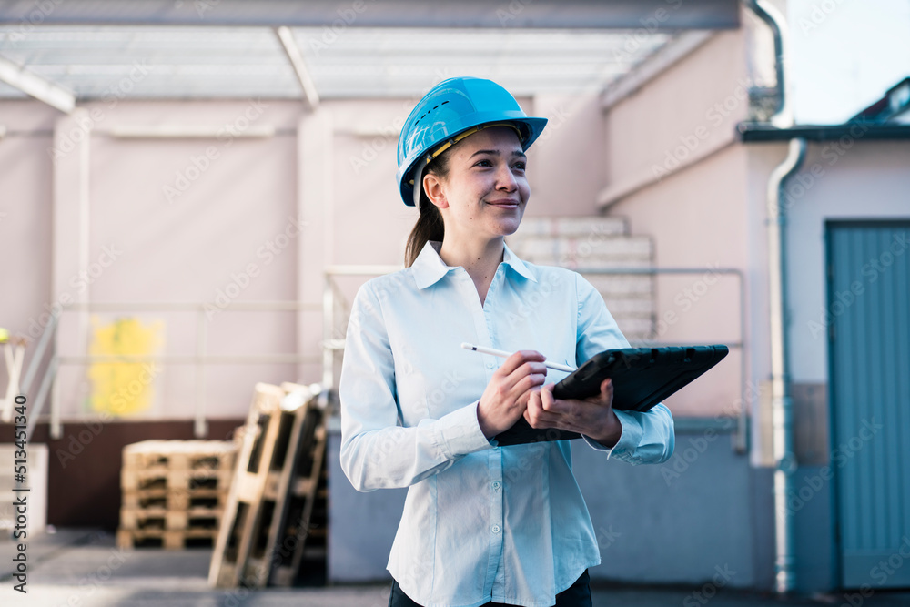 Smiling female architect with tablet PC at factory