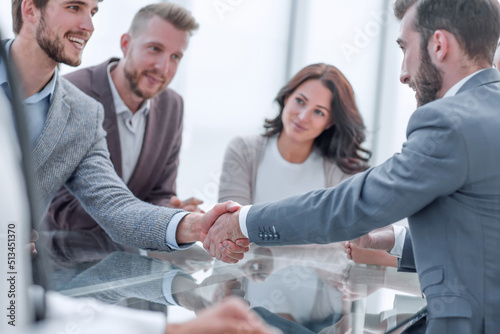 smiling business people shaking hands at a meeting