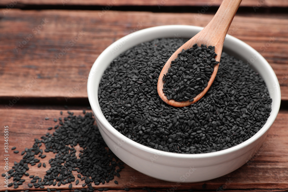 Bowl and spoon with black sesame on wooden table Bowl and spoon with black sesame on wooden table