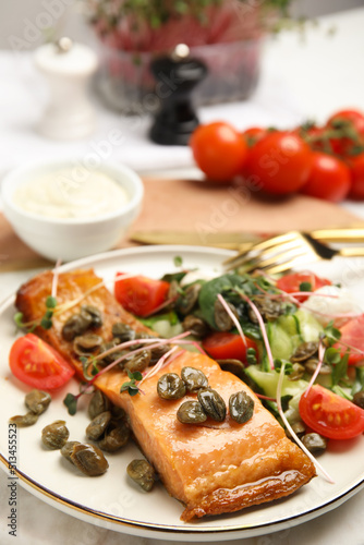 Delicious salmon with salad and capers on table, closeup