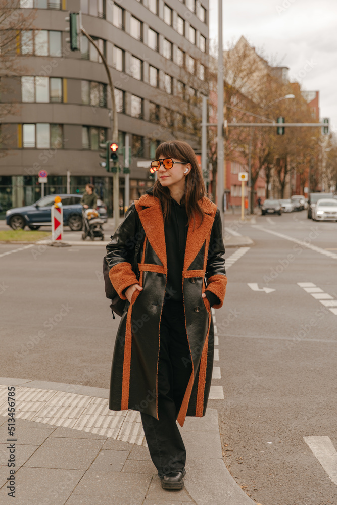 Full view of brunette woman walking on the street looking away Full view of brunette woman walking on the street looking away