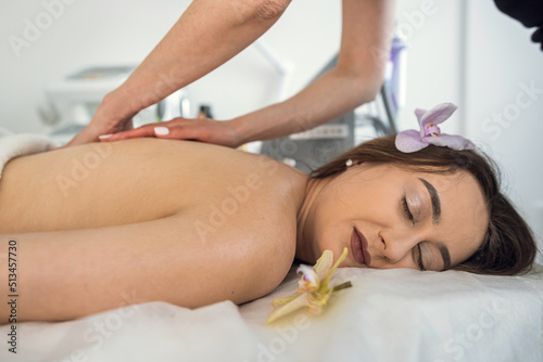 masseuse hands working massaging back in young beautiful woman client in the spa salon