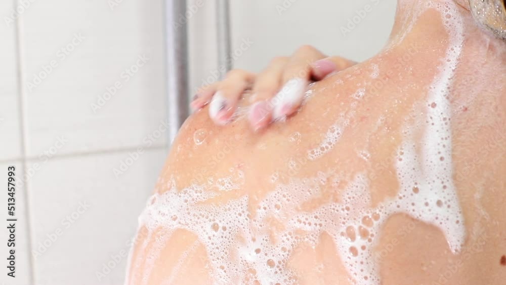 a woman in the foam in the shower washes. close-up a woman in the foam in the shower washes. close-up