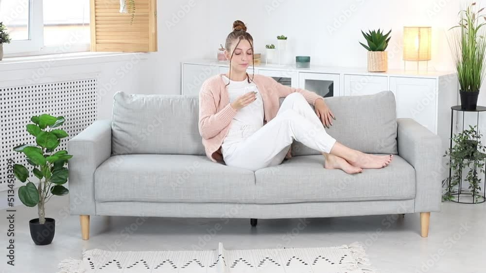woman pointing the remote up while sitting on the sofa in the living room woman pointing the remote up while sitting on the sofa in the living room