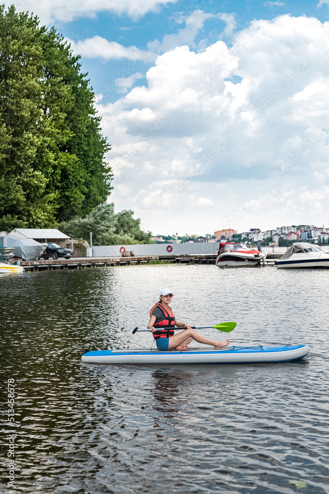 Young Woman wear Life vest rest on Paddle Board after the first training session