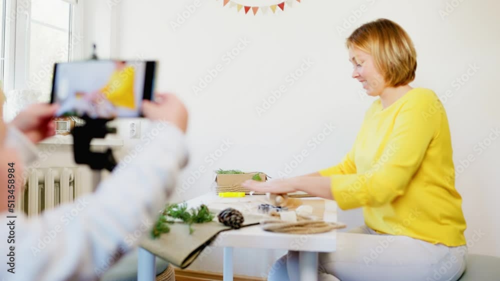 A little child touch smartphone screen while the video is being recorded. Movement of the camera from the smartphone screen to the woman cooks cookies at the table. Online streaming concept. A little child touch smartphone screen while the video is being recorded. Movement of the camera from the smartphone screen to the woman cooks cookies at the table. Online streaming concept.