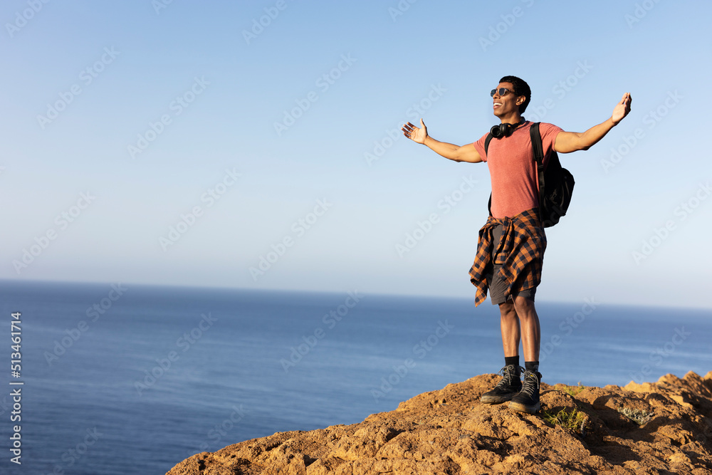 Young man standing on the stone with raised up arms. Tourist man on the top of the mountain. Young man standing on the stone with raised up arms. Tourist man on the top of the mountain.
