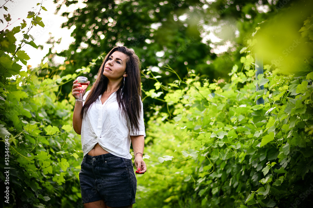 Young beautiful smiling woman in a Vineyard with a glass of rose wine during the summer vacation. Wine tourism Young beautiful smiling woman in a Vineyard with a glass of rose wine during the summer vacation. Wine tourism