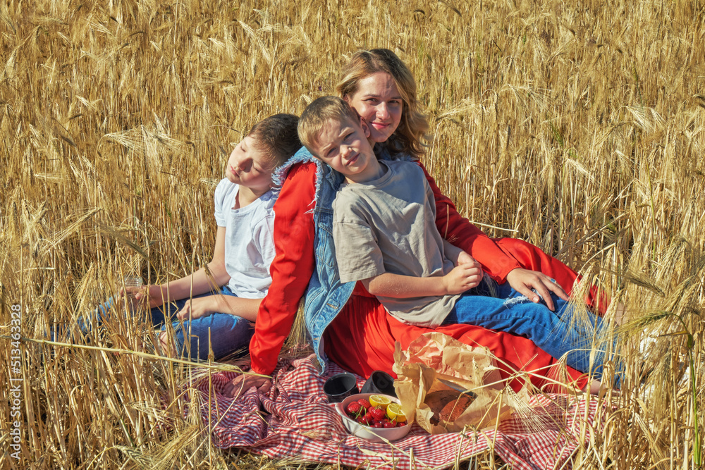 Young mother with children at a picnic in a wheat field