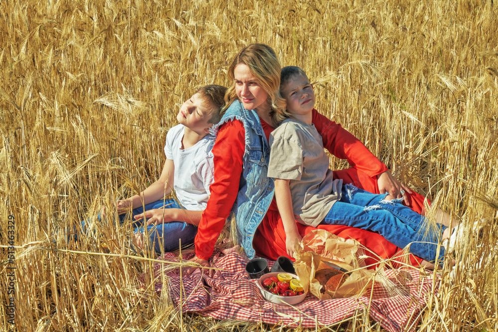 Young mother with children at a picnic in a wheat field