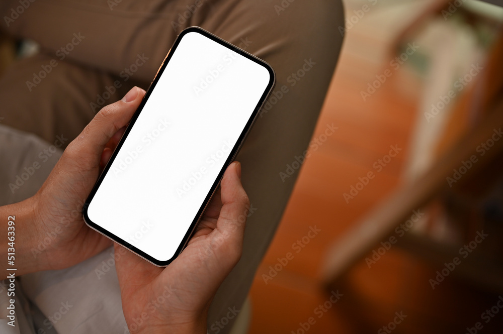 Top view, A smartphone with screen mockup is in a male's hands over his lap. Top view, A smartphone with screen mockup is in a male's hands over his lap.