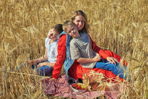 Obraz na płótnie Young mother with children at a picnic in a wheat field w salonie