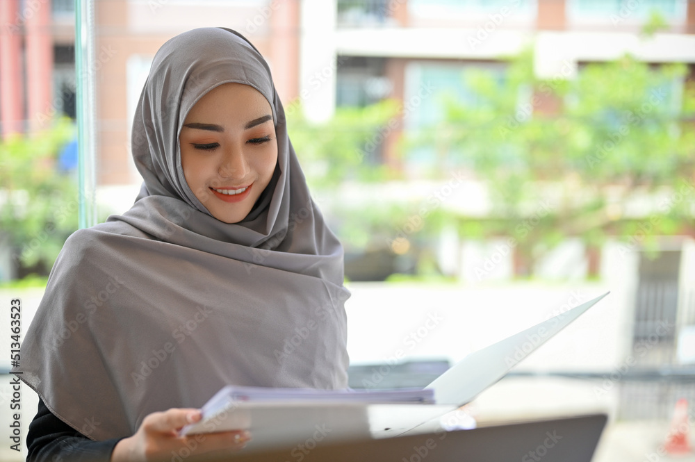 Attractive muslim female college student or businesswoman in hijab working on her task. Attractive muslim female college student or businesswoman in hijab working on her task.