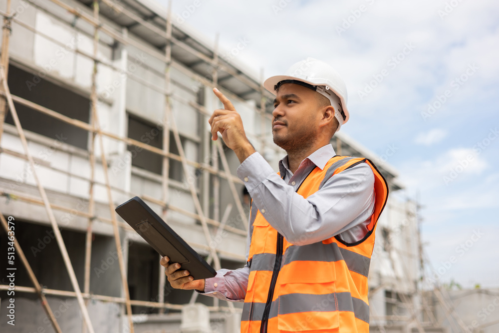 Confident asian engineer man Using tablet for checking and maintenance to inspection at modern home building construction. Architect working with white safety helmet in construction site Confident asian engineer man Using tablet for checking and maintenance to inspection at modern home building construction. Architect working with white safety helmet in construction site