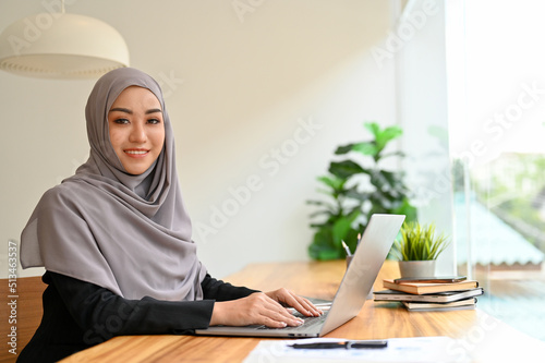 Portrait of a beautiful muslim businesswoman with hijab using laptop computer