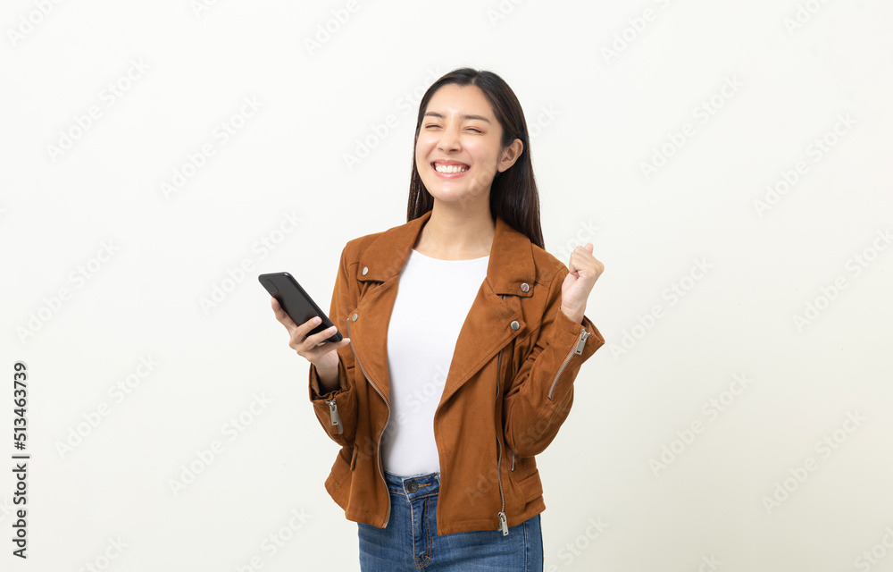 Pretty young asian woman using smartphone standing on isolated white background. She texting on cell phone. Dressing with jacket and jean. Pretty young asian woman using smartphone standing on isolated white background. She texting on cell phone. Dressing with jacket and jean.
