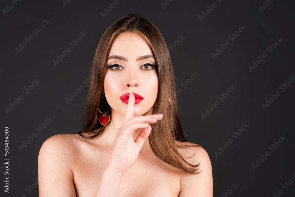 Womens secrets. Woman showing secret sign. Female with finger in mouth. Closeup portrait of young woman is showing a sign of silence with shhh. Beauty portrait of beautiful female model. Womens secrets. Woman showing secret sign. Female with finger in mouth. Closeup portrait of young woman is showing a sign of silence with shhh. Beauty portrait of beautiful female model.