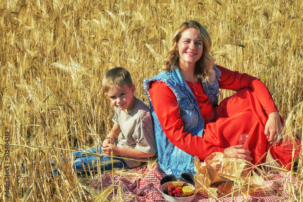 Young mother with children at a picnic in a wheat field