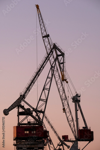 A silhouette of an old shipyard crane against the sunset